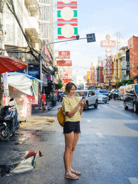 istock Woman using smartphone while walking in Chinatown in Bangkok 2055649211