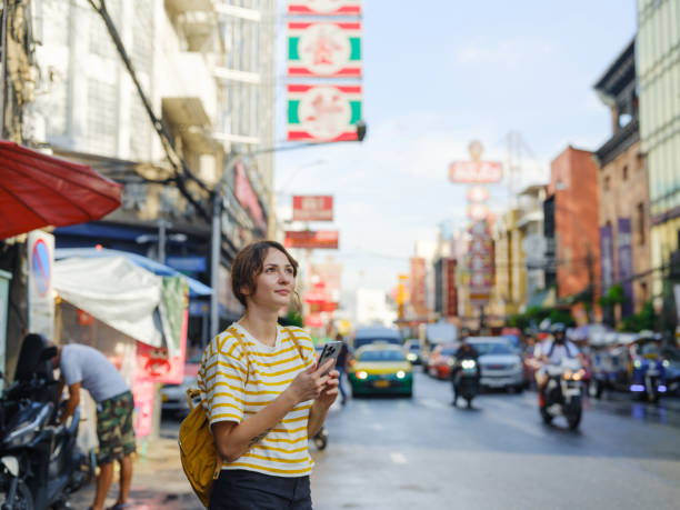 istock Woman using smartphone while walking in Chinatown in Bangkok 2055649385
