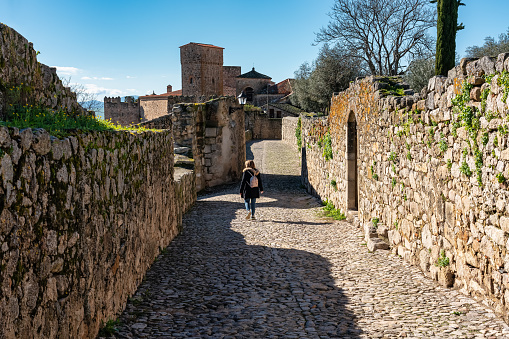 Female tourist strolling through the narrow streets of the medieval stone town of Trujillo