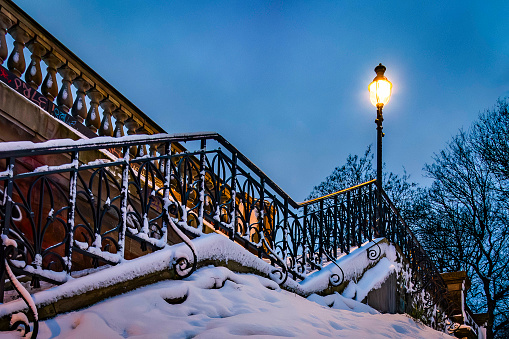 Staircase railing and glowing lantern at Lombardsbrücke in winter