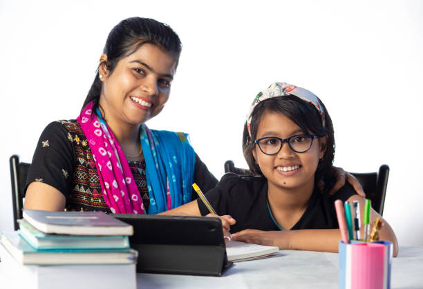Studying at home An Indian girl student studying with tablet besides her mother, teacher: private teacher concept assignment homework stock pictures, royalty-free photos & images