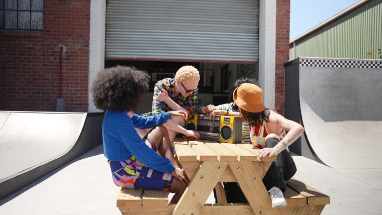 Smiling friends sitting at picnic table with boom box