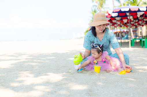 Mother and girl playing in the sand on the beach, Pattaya, Thailand,Mother with children playing with sand on beach