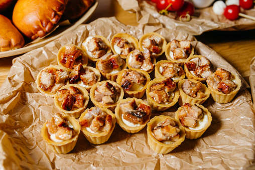 Delicate tartlets filled with cream cheese and topped with caramelized eel, presented on a paper-lined tray.