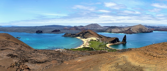Galapagos, Ecuador, October 24, 2022: Panoramic  view of the coastline of the Bartolomé island with its Pinnacle Rock under cloudy sky.