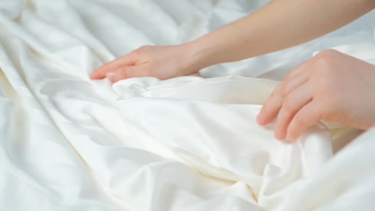 Woman touching the fabric of stripe satin with her hand, gently stroking, close-up.