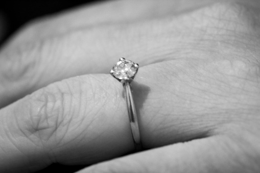 A closeup of a woman's hand wearing an engagement ring