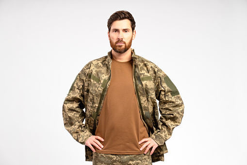 Handsome bearded man, soldier wearing camouflage military uniform holding looking at camera isolated on white background