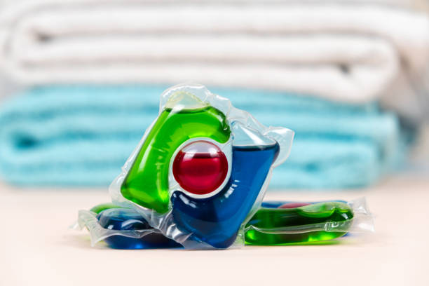 istock Laundry pods capsules on beige background with soft towels 2055824703