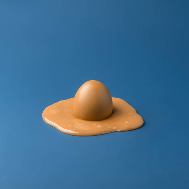 Creative easter concept. Brown chicken egg melts in brown paint on blue background.