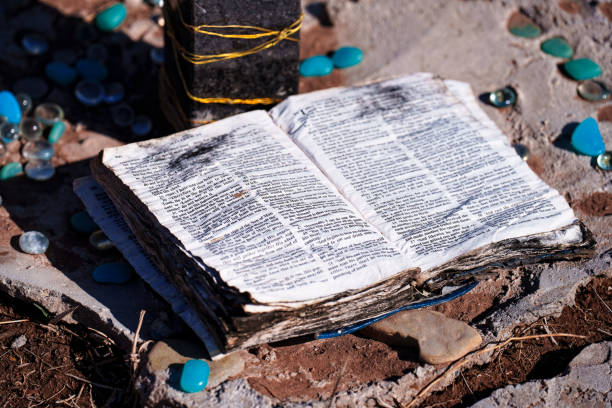 Weathered Bible at Outdoor Memorial - Detail of wet distressed bible left at outdoor memorial in natural setting. Closeup detail with selective focus. Bible open to the Book of Matthew.