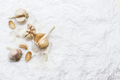 Unpeeled heads and cloves of garlic. Copy space. White background. Flat lay