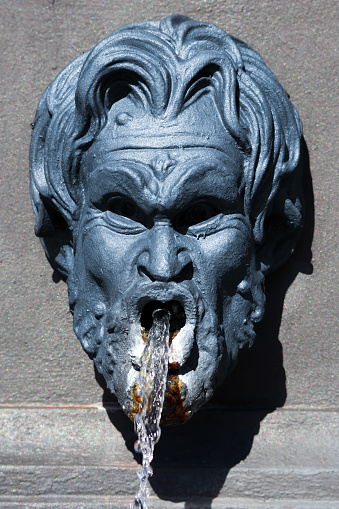 Popoli (Italy): water flowing from the mouth of one of the grotesque faces in cast iron on the sides of the Fontana dei Mascheroni (Fountain of the Grotesque Faces), in Piazza della Libertà, the main square of the town of Popoli, in the Pescara province of Abruzzo, in Italy
