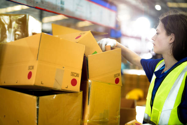 istock Warehouse woman worker folding paper box for packing the items in a large warehouse. man sealing cardboard boxes for shipping in cargo product stock. 2055859714
