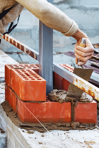 Industrial Bricklayer Installing Bricks at Construction Site. Close-up