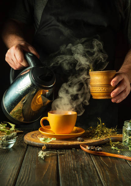istock Making healthy green tea from dry medicinal herbs. Adding boiling water to a mug with herbs. Traditional medicine concept. Treating the flu virus at home 2055901371