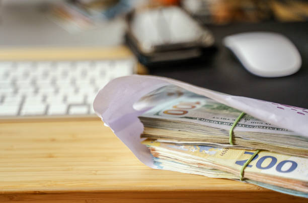 Envelope filled with stack of hundred dollar and Euro bills