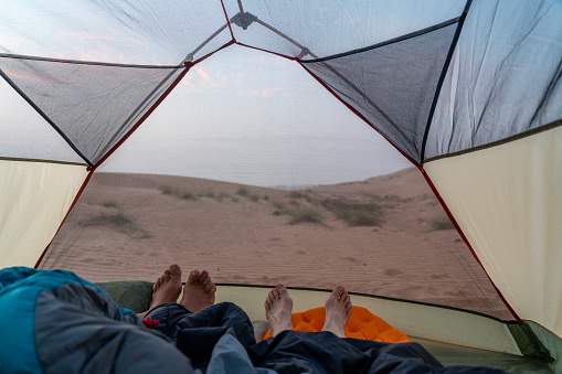 Couple, just feet visible, in small tent in the morning in Wahiba desert in Oman