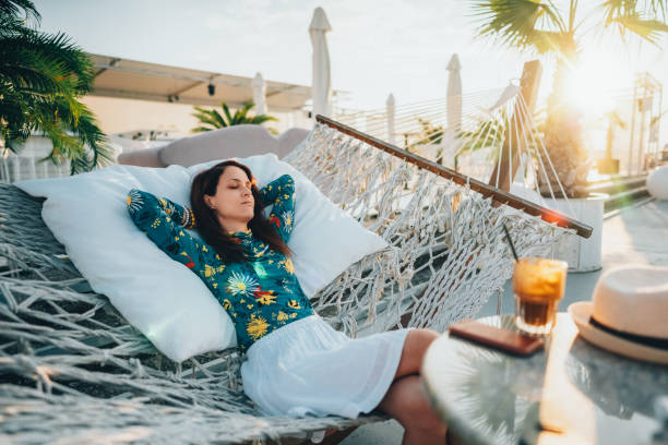 view of woman relaxing on hammock. Low angle view. Beautiful female feet relaxing in a hammock on the beach against the background of the sky. horizontal is place for your text