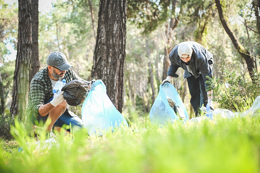 male volunteers collecting garbage in the forest