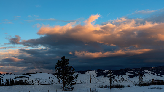 Sunset cloudscape with a field of snow and mountains