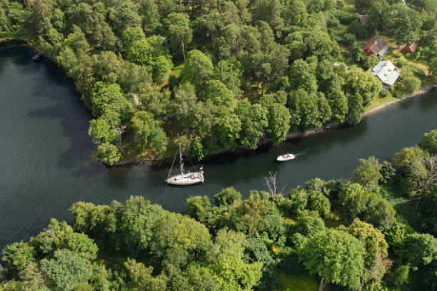 A sailboat and a motorboat travelling through a canal in summer towards the Baltic Sea in the Nacka municipality outside Stockholm.