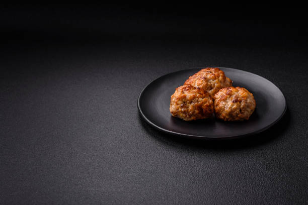 Delicious fresh fried minced fish cutlets with spices and herbs on a dark concrete background