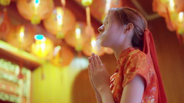 asian young girl praying respect to budha when chinese new year at temple with lantern decorated.