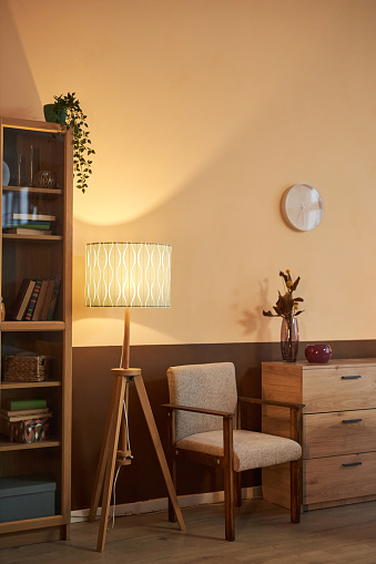 Vertical full length shot of cozy reading nook and sitting area with wooden chair and tall lamp