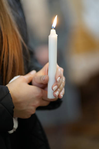 istock A woman holds a burning candle during a religious service. 2056052774