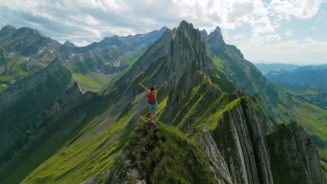 Aerial view of woman standing on the top of mountain ridge in Switzerland