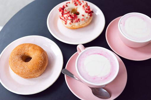 Donuts on a pink plate with pink coffee.