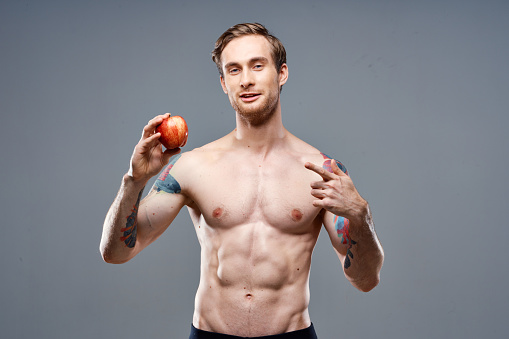 Man with apple and sport healthy food pumped up cake bodybuilder. High quality photo