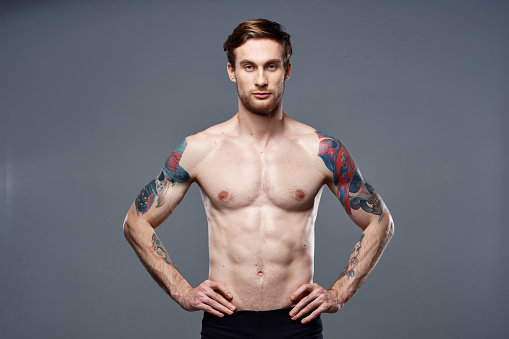 athletic man with pumped up abs tattoos on his arms. High quality photo