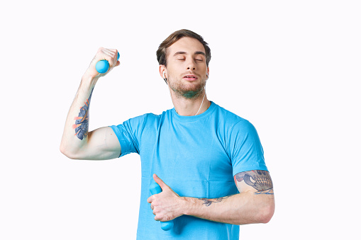 man with dumbbells pumped up arm muscles smile model tattoo blue t-shirt. High quality photo