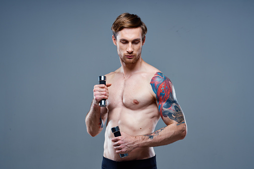 handsome man blond Sport Fitness pumped-up torso dumbbells model. High quality photo