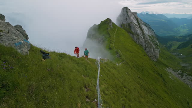 Aerial view of man and woman hiking on top of mountain ridge in Switzerland