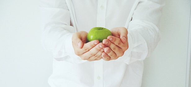A man in a shirt holding a green apple