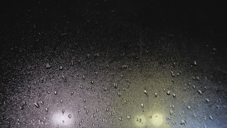 Drops of rain on the window in the rays of night illumination