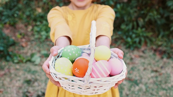 Easter egg hunt. Excited emotion surprise adorable child girl in bunny ears rabbit costume hold basket with Easter colored eggs. Children positive emotions. Kid happy Easter. Egg hunting outside