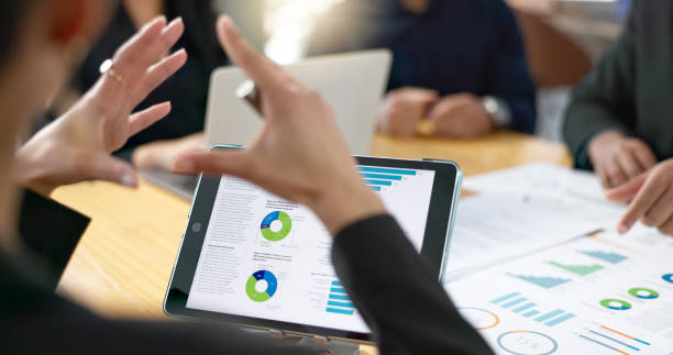 istock People, meeting and tablet screen of data analytics, graphs and statistics in finance, business or revenue proposal. Professional employees, analyst or manager talking of digital sales and documents 2056252921