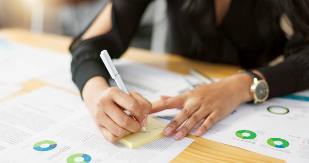 istock Hands, business person and data analysis, writing on sticky note and paperwork review with graphs and information. Statistics, analytics and infographic documents with planning and market research 2056252930