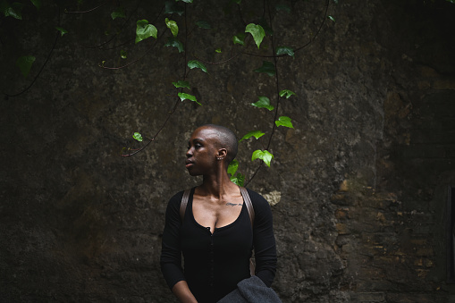 side view portrait of a serious black woman standing outdoors.