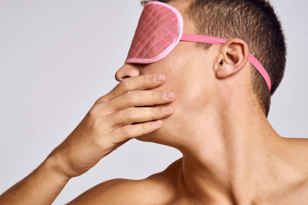 istock A man in a pink mask for sleeping on a light background at night gestures with his hands 2056257287