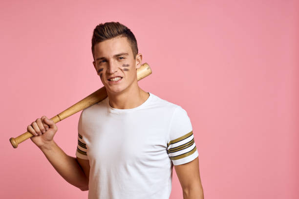 istock Energetic man with a bat on a pink background T-shirt face make-up black lines aggression model 2056290259