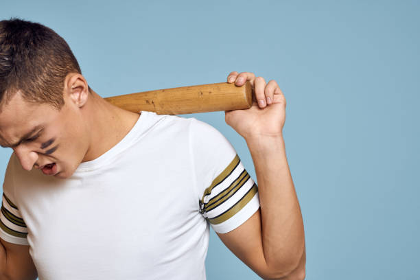 istock baseball guy with a bat in his hand on a blue background and a combat color on his face makeup model t-shirt 2056300614