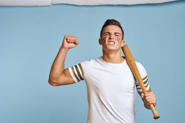 istock baseball guy with a bat in his hand on a blue background and a combat color on his face makeup model t-shirt 2056313301
