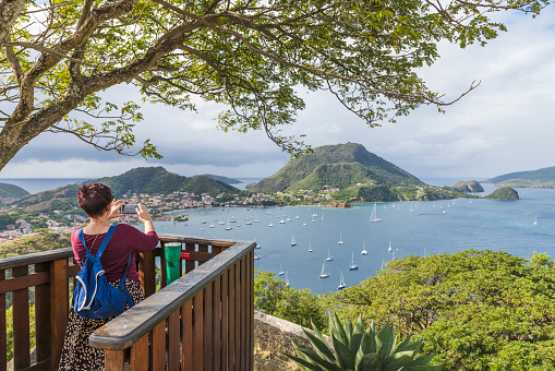 A woman is photographing Les Saintes Bay from Napolean Fort, Terre-de-Haut, Iles des Saintes, Guadeloupe on 12th February 2024.