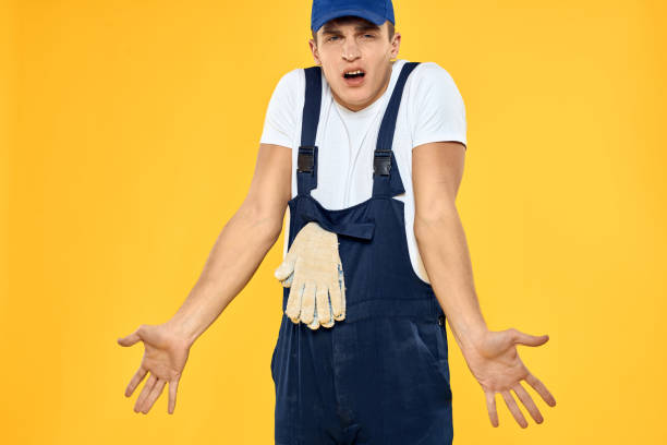 istock Working man in uniform of gloves rendering service yellow background 2056335710