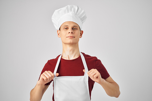man in a white apron with a cap on his head working uniform kitchen. High quality photo
